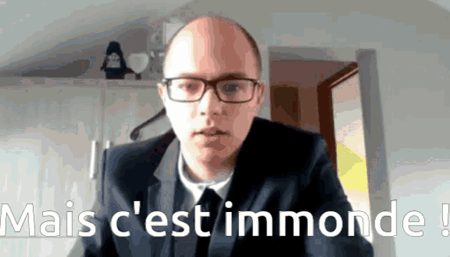 a man wearing glasses and a suit says mais c ' est immonde