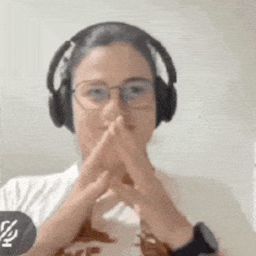 a woman wearing headphones and glasses making a gesture with her hands