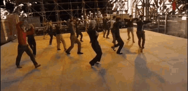 a group of people are dancing on a stage in a circle .