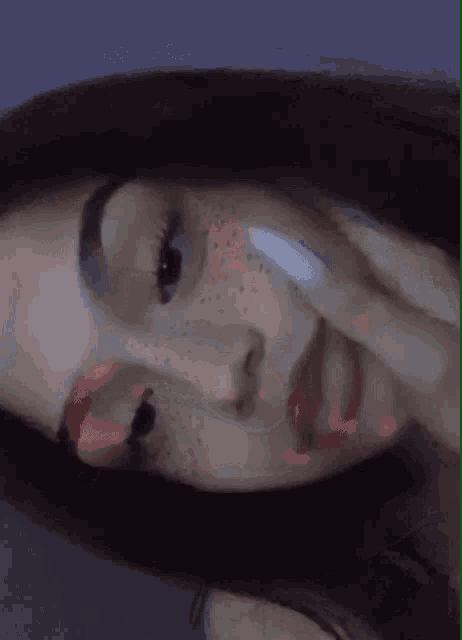 a girl with freckles on her face is taking a picture of herself with her hand on her face .