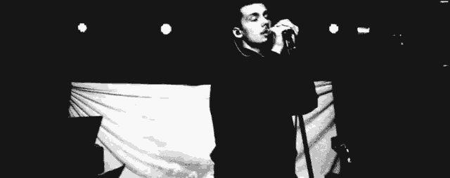 a man singing into a microphone in a black and white photo