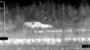 a black and white image of a plane flying over a forest .