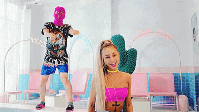 a man wearing a pink ski mask is dancing next to a woman in a pink top .