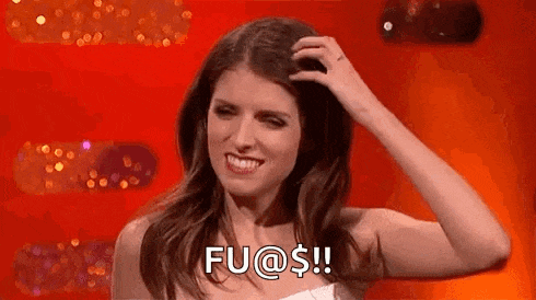 a woman is smiling and scratching her head while standing in front of a red wall .