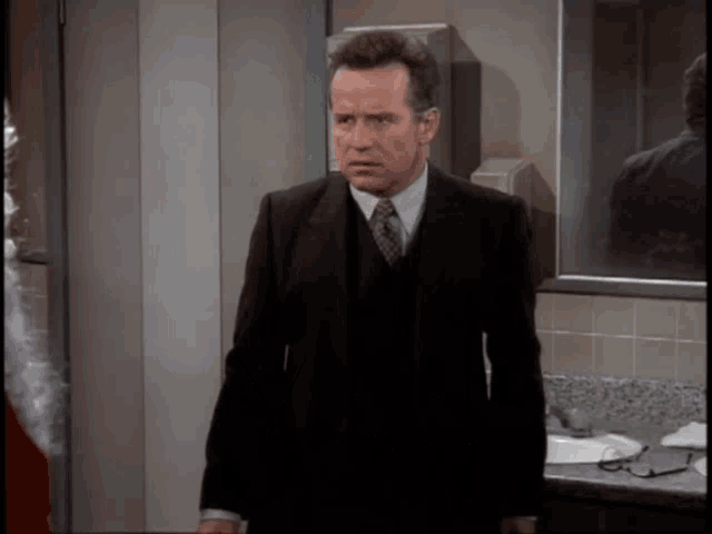 a man in a suit and tie stands in front of a sink