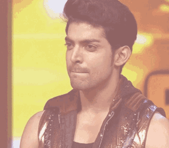 a man in a brown vest is looking at the camera
