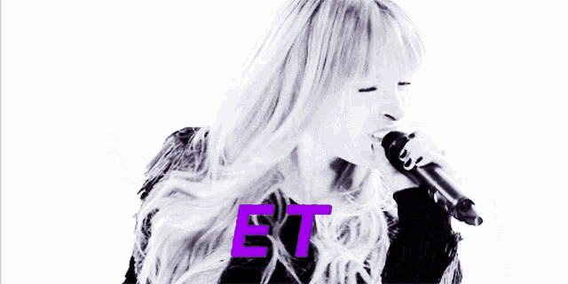 a woman singing into a microphone with the letters et on the bottom