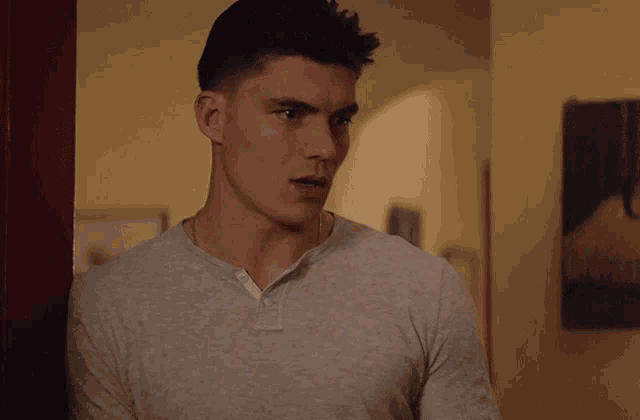a man in a grey shirt stands in a doorway