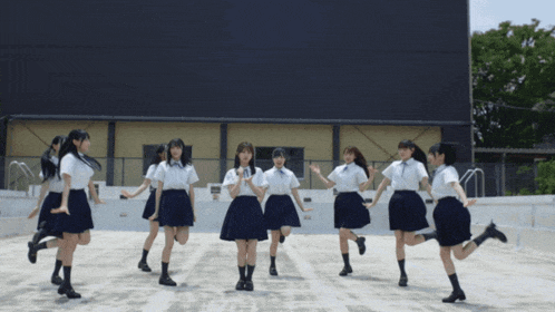 a group of girls are dancing in front of a large building