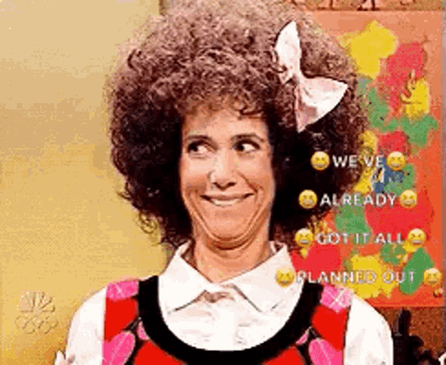 a woman with curly hair and a bow in her hair is smiling and making a funny face .