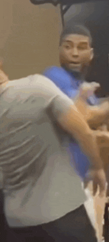 a man in a blue shirt is fighting another man in a white shirt .