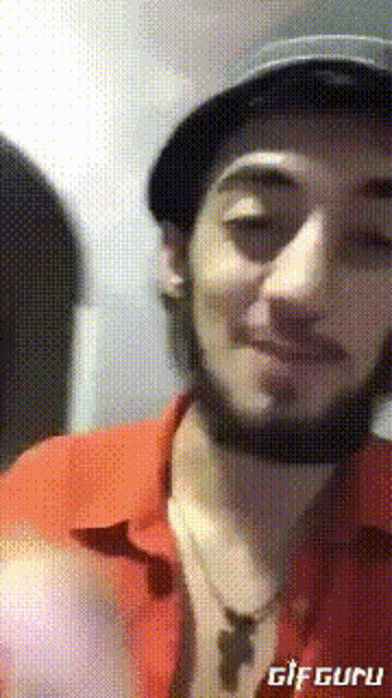a man with a beard wearing a hat and a red shirt with the word gifguru on the bottom right