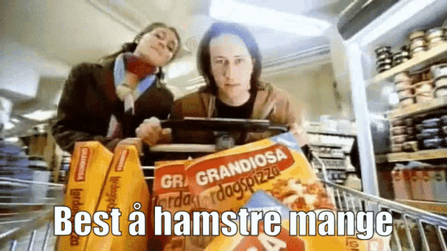 a woman pushing a shopping cart with boxes of grandiosa pizza in it