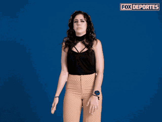 a woman stands in front of a blue background that says fox deportes on it