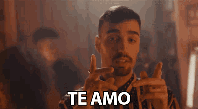 a man in a striped shirt says te amo in a dark room