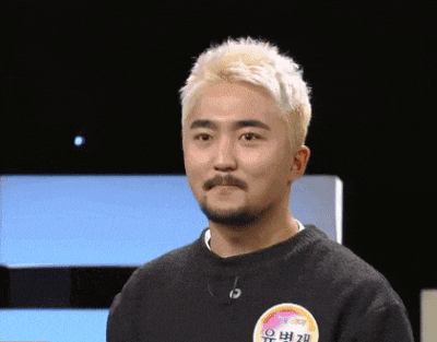 a man with blonde hair and a beard is wearing a black sweater with a sticker on it that says " o "