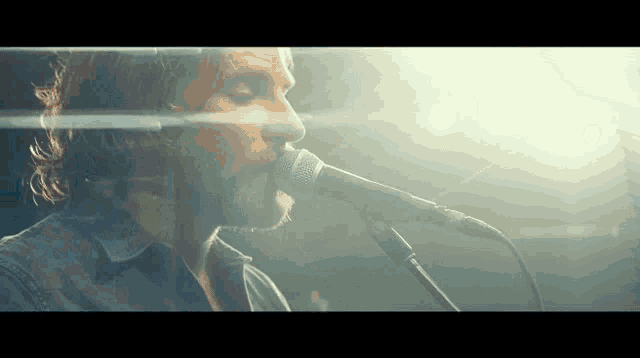 a close up of a man singing into a microphone with his eyes closed