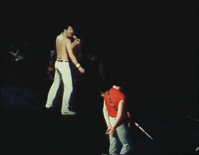 a man in a red shirt stands next to a man playing a guitar on a stage