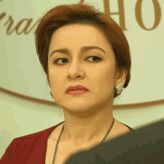 a woman wearing earrings and a necklace is looking at something