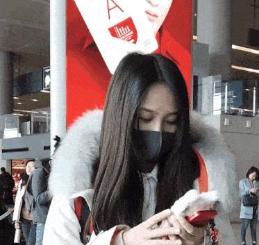 a woman wearing a face mask looks at her phone