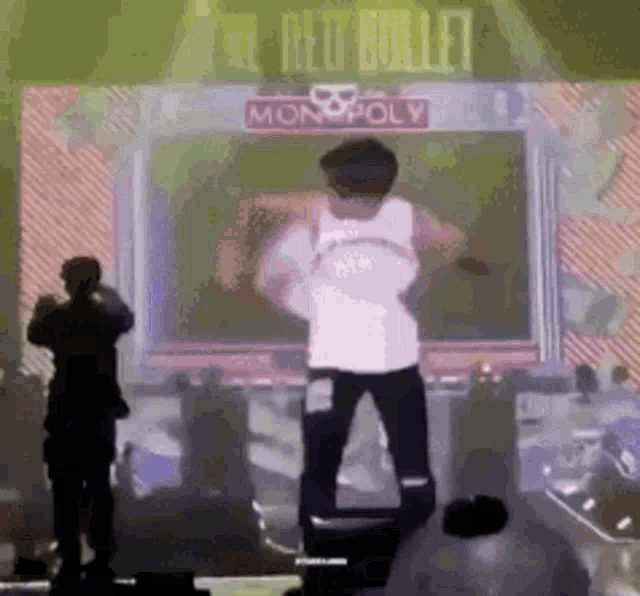 a man is standing on a stage in front of a monopoly sign .
