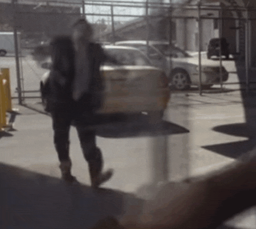 a person is walking in front of a yellow taxi