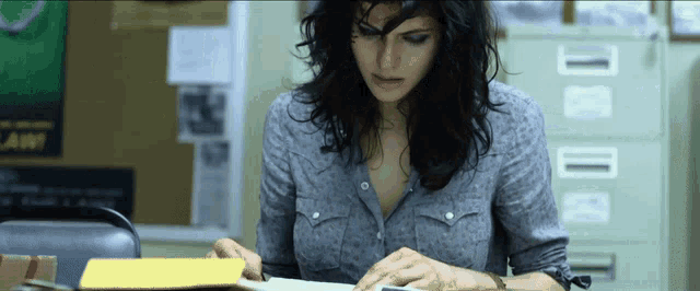 a woman sits at a desk in front of a filing cabinet with a sign that says law on it
