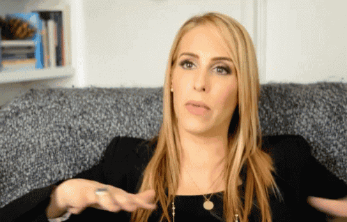 a woman is sitting on a couch with her hand out