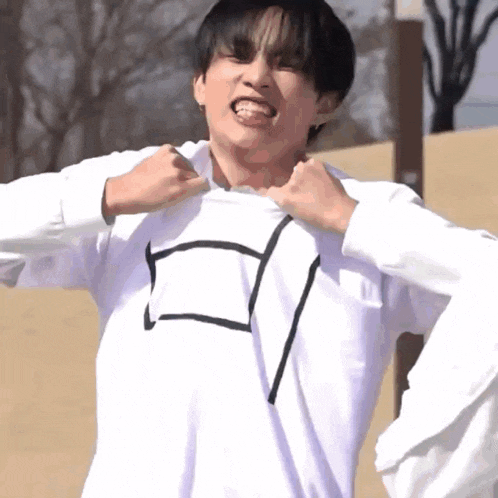 a young man wearing a white sweatshirt with a black square on it is making a funny face .