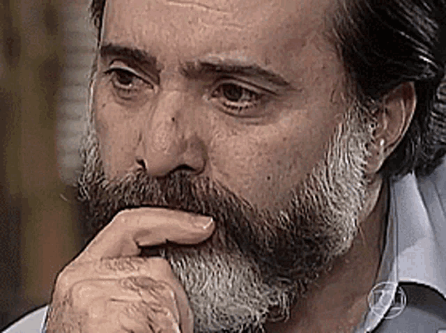 a man with a beard is thinking with his hand on his chin ..