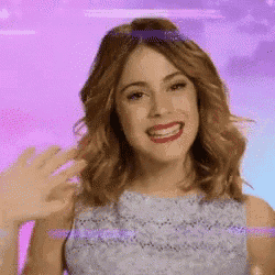 a woman in a blue dress is smiling and waving her hands .