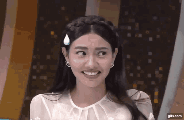 a woman in a white dress is smiling and making a face .