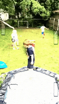 a boy standing on a trampoline in a backyard