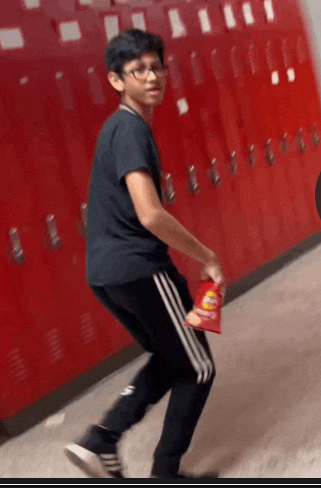 a boy in a black shirt is holding a bag of doritos