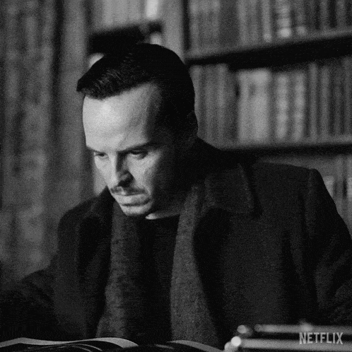 a black and white photo of a man reading a book with netflix written on the bottom right