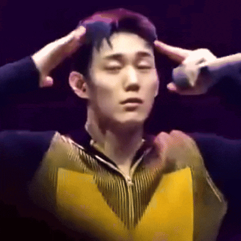a man in a yellow jacket is holding his hands to his head while another person holds a microphone .