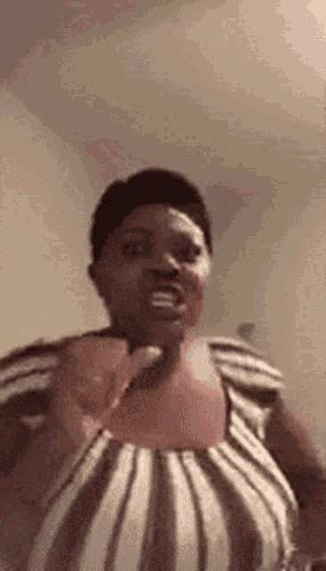 a woman in a striped shirt is making a funny face while pointing at the camera .