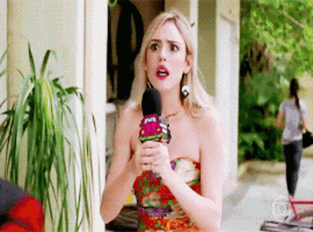 a woman is holding a microphone with a sticker on it that says ' a ' on it