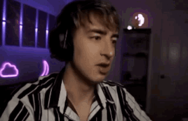 a man wearing headphones and a striped shirt is sitting in front of a computer .