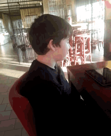 a young boy sitting at a table with a tablet on it