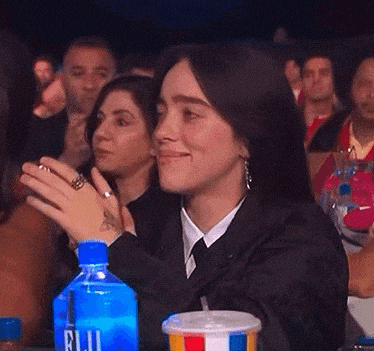 a woman sitting in a crowd with a bottle of fuji water