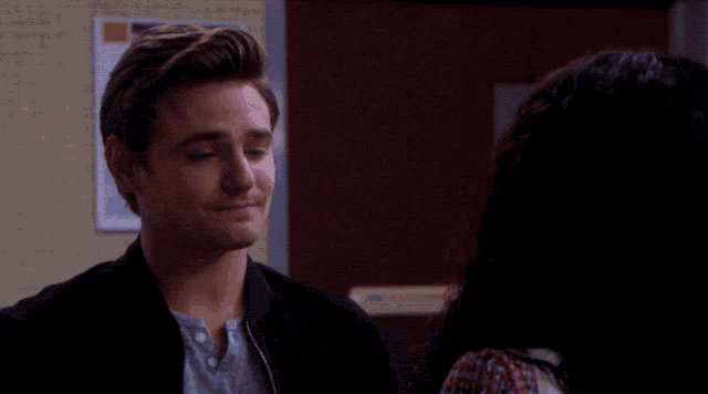 a woman with hoop earrings looks at a man in a black shirt