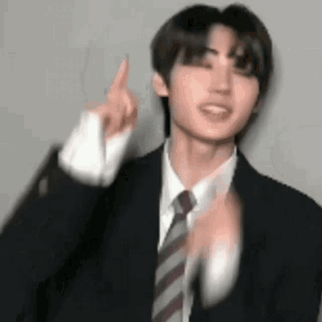 a man in a suit and tie is pointing his finger up .