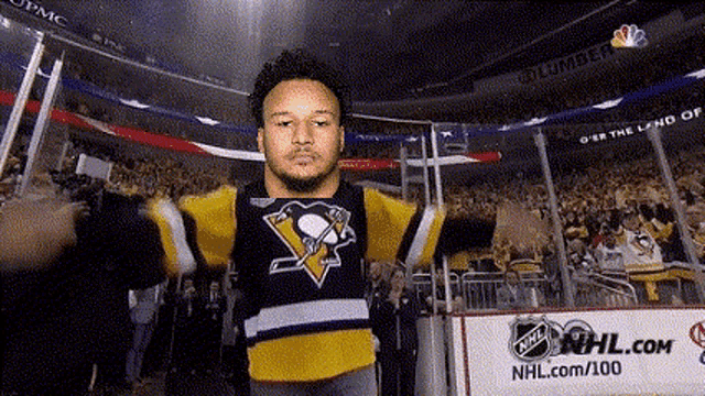 a man in a pittsburgh penguins jersey stands in front of a crowd