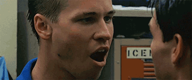 two men are looking at each other in front of a locker with the word ice on it