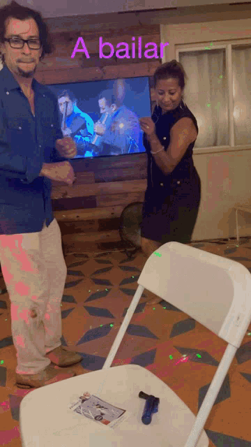 a man and woman are dancing in front of a tv that says a bailar on it