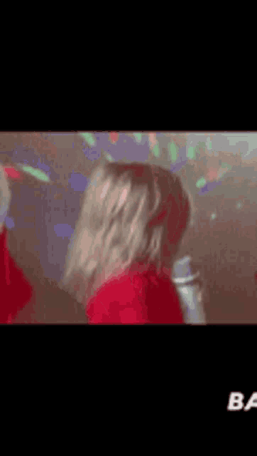 a little girl in a red sweater is holding a microphone in her hand .