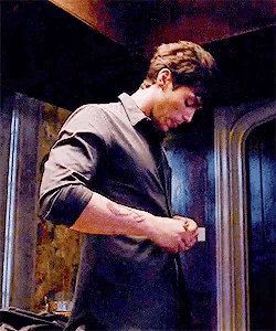 a man in a black shirt is standing in a dark room .