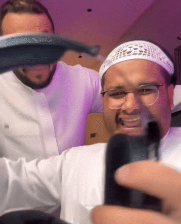 a man wearing glasses and a headband is taking a picture of himself with another man