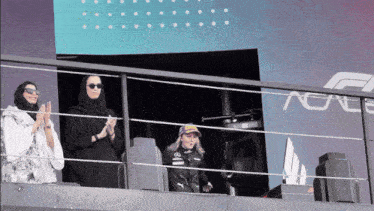 a woman wearing a mercedes branded jacket applauds
